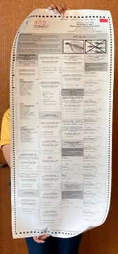 Example of a large-print ballot. A Recorder's Office employee is holding the ballot that stretches from the top of her head to her knees